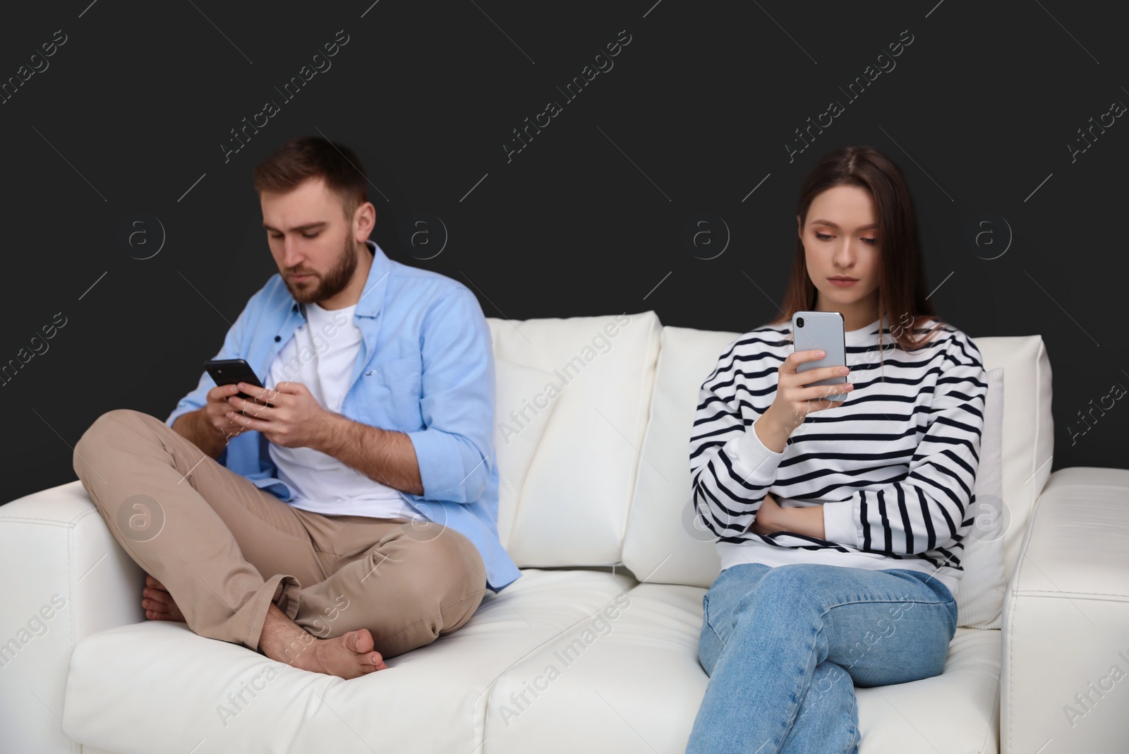 Photo of Couple addicted to smartphones ignoring each other at home. Relationship problems