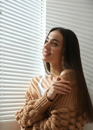 Photo of Young woman near window with Venetian blinds