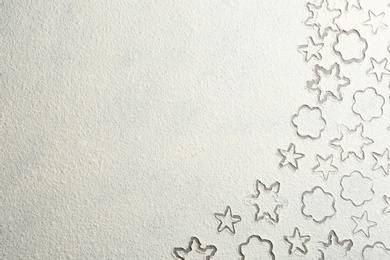 Different Christmas cookie shapes made of flour on grey table, top view. Space for text