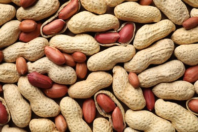 Photo of Many fresh unpeeled peanuts as background, top view