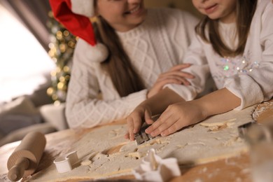 Photo of Mother with her cute little daughter making Christmas cookies in kitchen, closeup