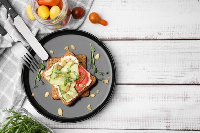 Tasty vegan sandwich with cucumber, tomato, pumpkin seeds served on white wooden table, flat lay. Space for text