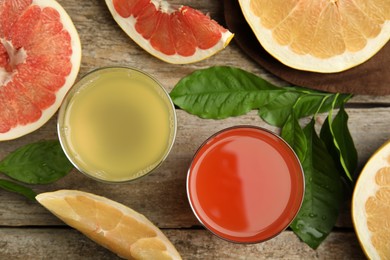 Glasses of different pomelo juices and fruits on wooden table, flat lay