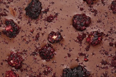 Photo of Chocolate bar with freeze dried blackberries as background, closeup