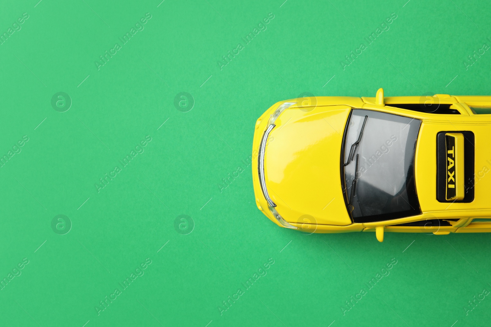 Photo of Yellow taxi car model on green background, top view. Space for text