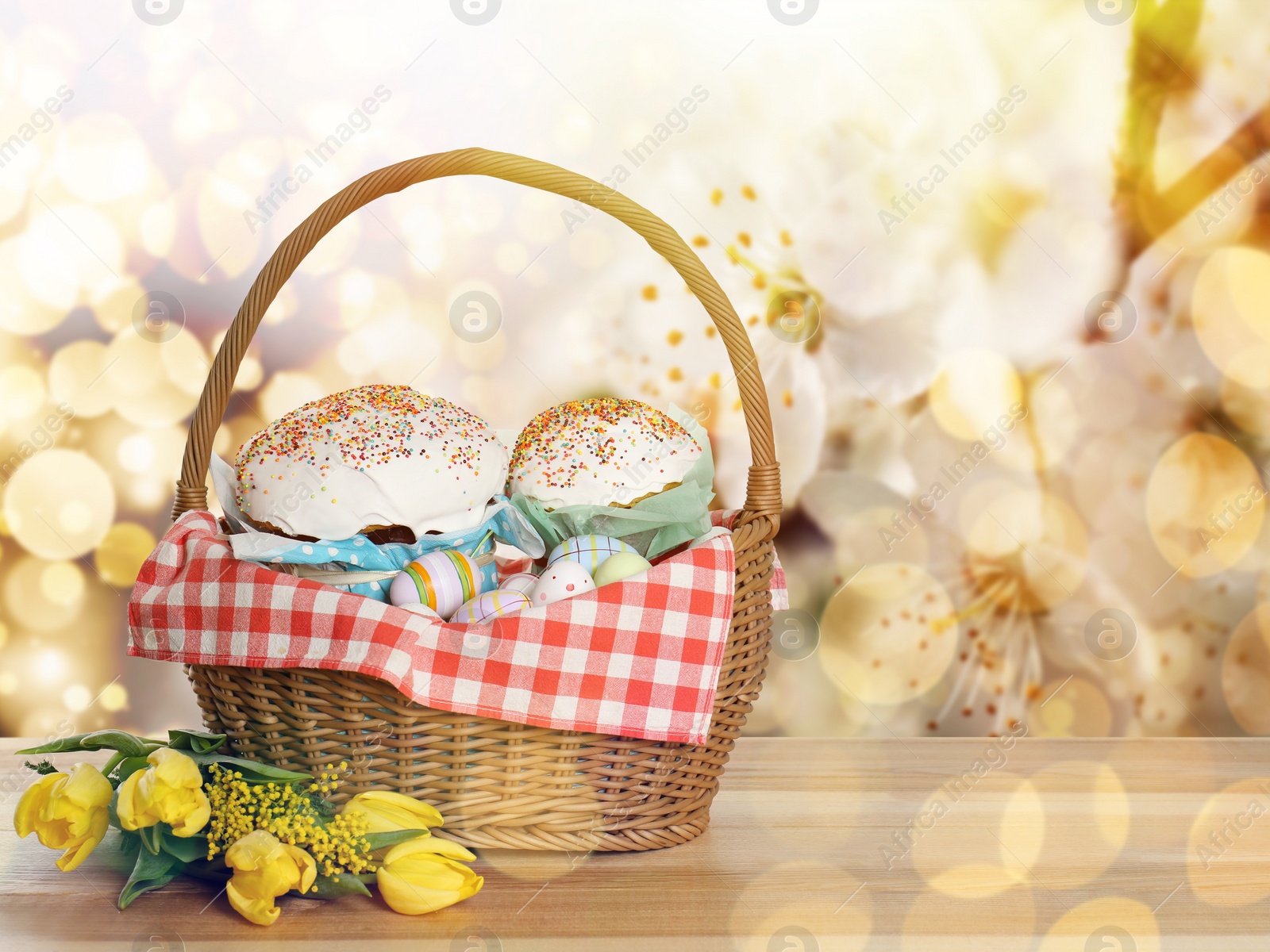 Image of Basket with delicious Easter cakes, painted eggs and flowers on wooden table. Space for text