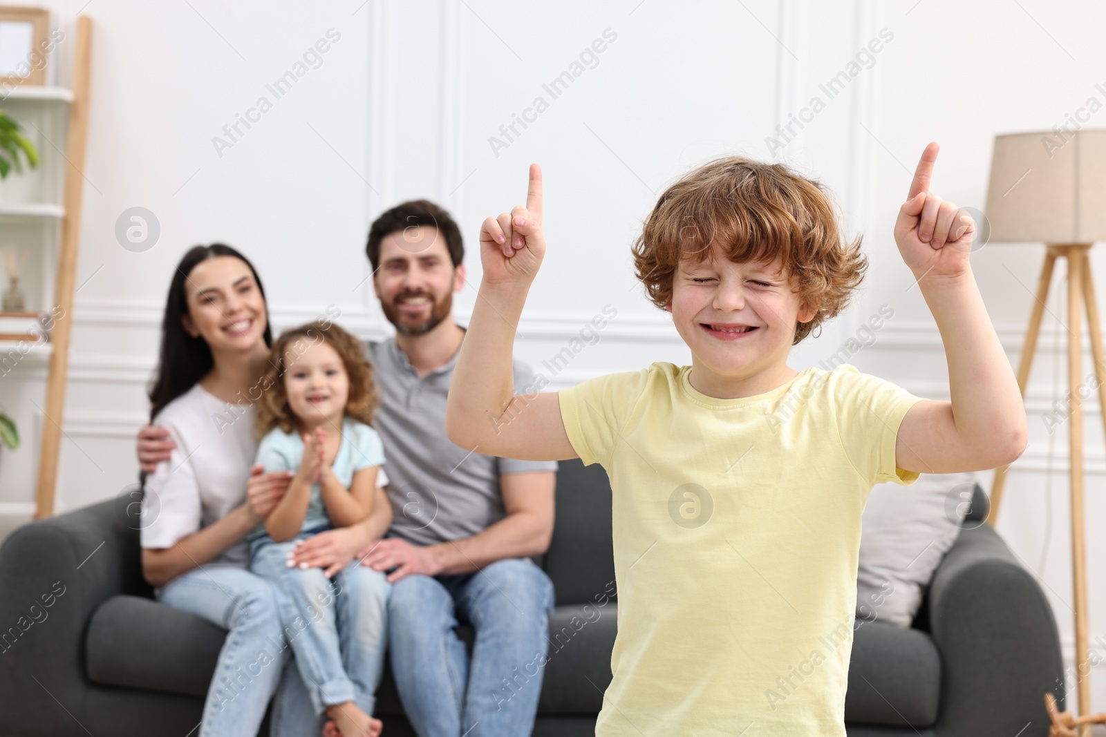 Photo of Happy family having fun at home. Son dancing while his relatives resting on sofa