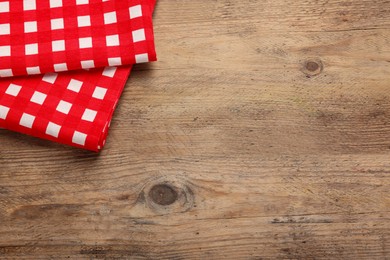 Photo of Checkered tablecloth on wooden table, above view. Space for text
