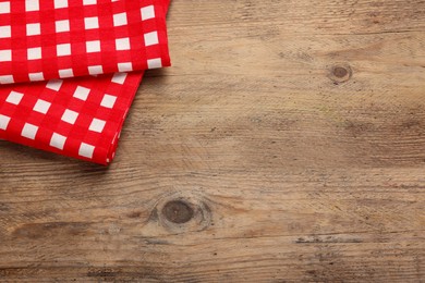 Checkered tablecloth on wooden table, above view. Space for text