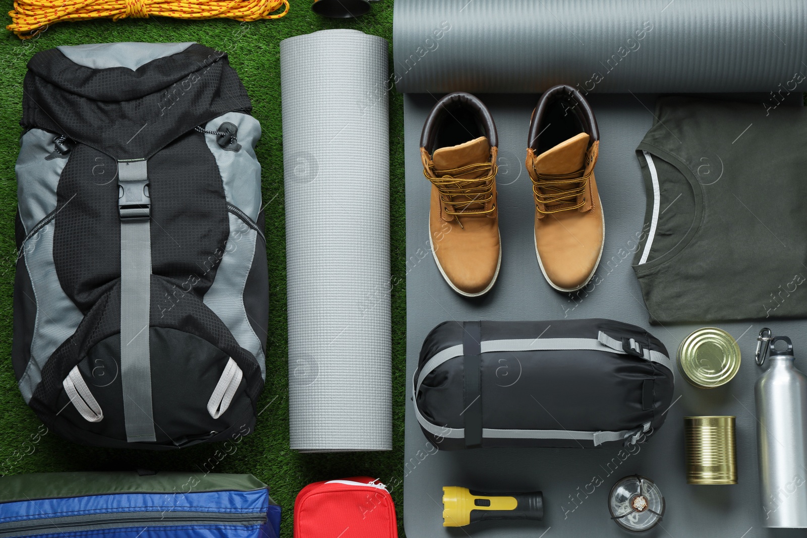 Photo of Flat lay composition with different camping equipment on green grass