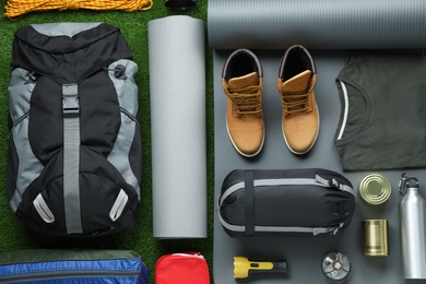 Flat lay composition with different camping equipment on green grass