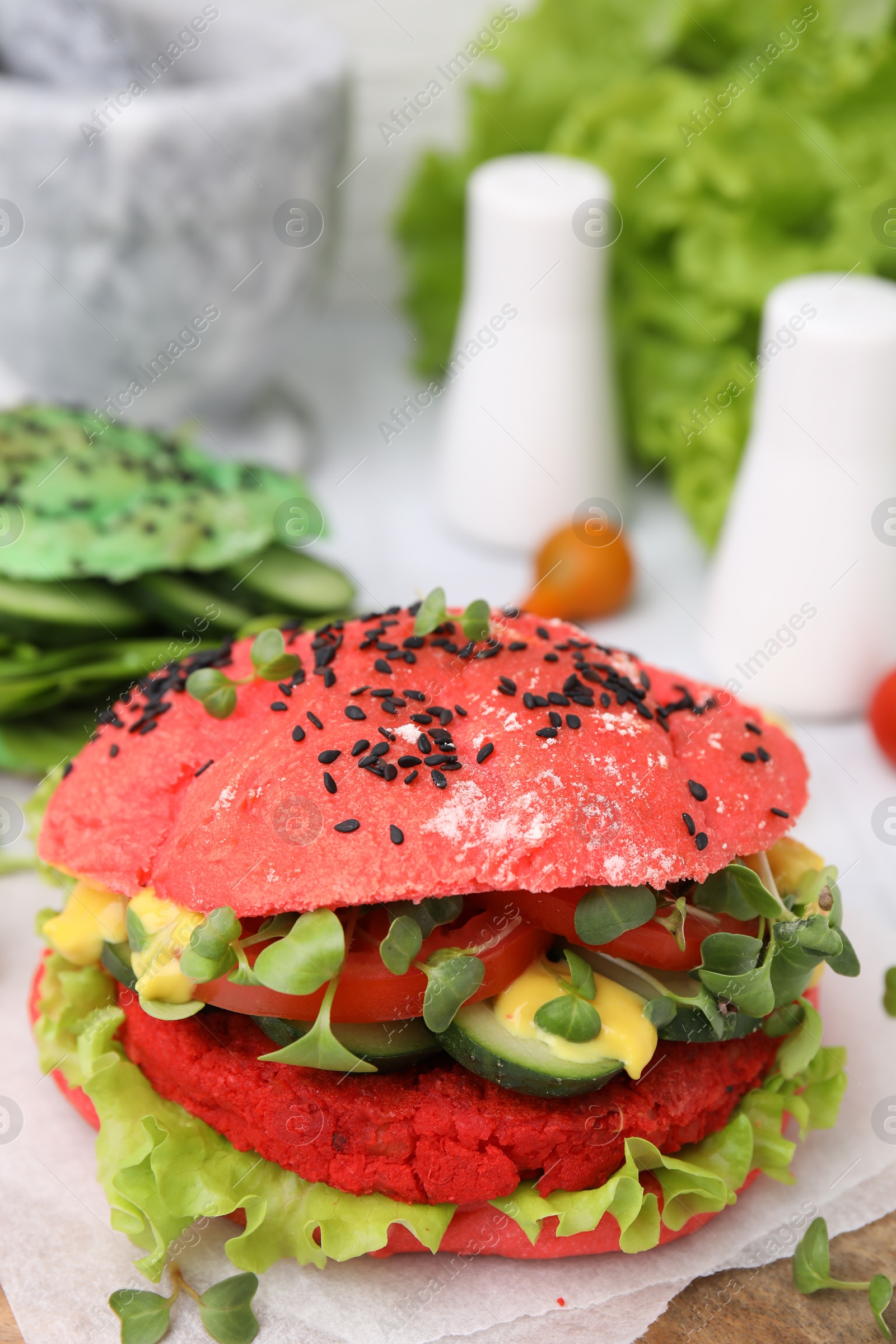 Photo of Tasty pink vegan burger with vegetables, patty and microgreens on white table, closeup