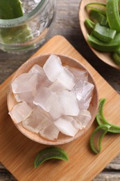 Aloe vera gel and slices of plant on wooden table, flat lay