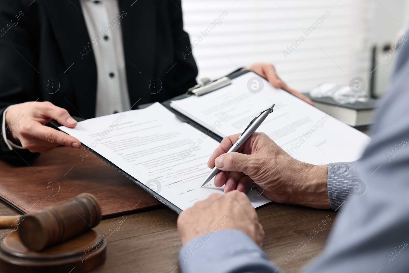 Photo of Senior man signing document in lawyer's office, closeup