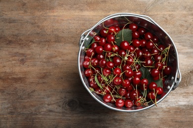 Photo of Bucket of delicious cherries on wooden table, top view. Space for text