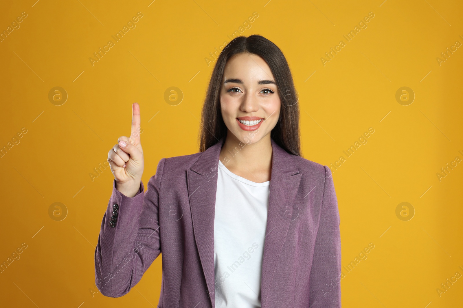 Photo of Woman in violet blazer showing number one with her hand on yellow background