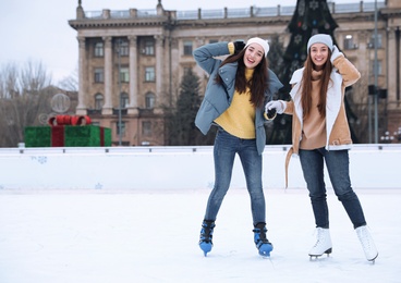 Image of Happy women skating along ice rink outdoors. Space for text
