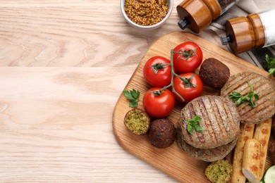 Photo of Different tasty vegan meat products and fresh vegetables on wooden table, flat lay. Space for text