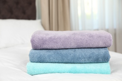 Stack of folded clean soft towels on bed