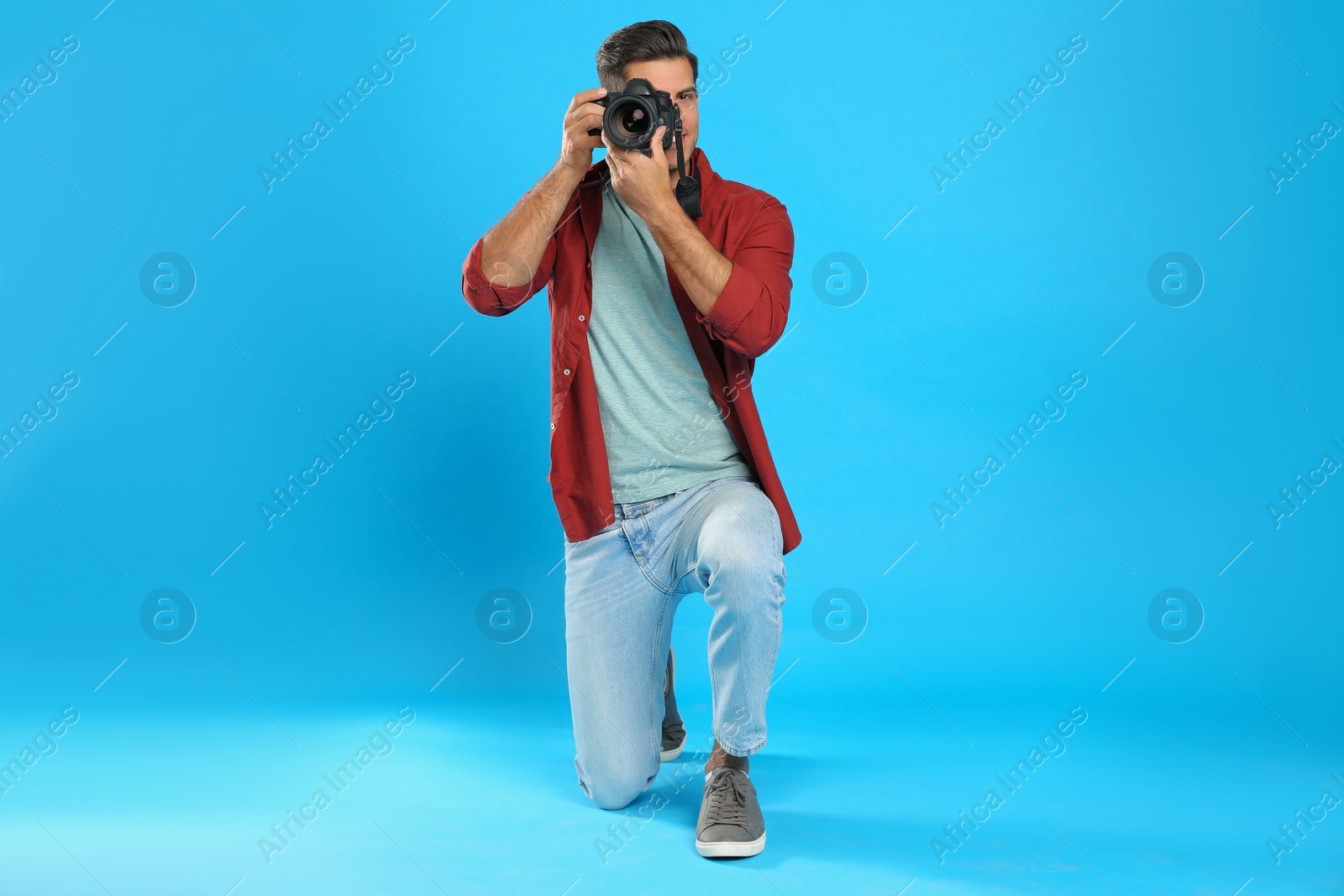 Photo of Professional photographer working on light blue background in studio