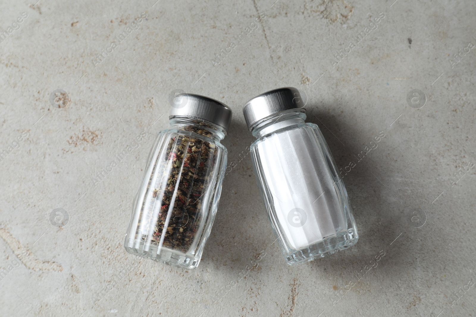 Photo of Salt and pepper shakers on light textured table, top view