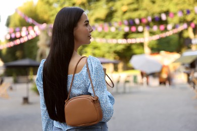 Photo of Young woman with stylish bag outdoors, space for text