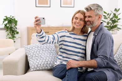 Happy affectionate couple taking selfie on sofa at home. Romantic date