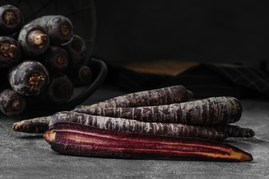 Fresh raw black carrots on grey table