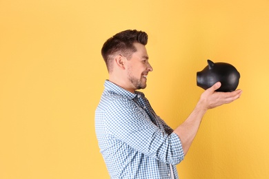 Man with piggy bank on color background