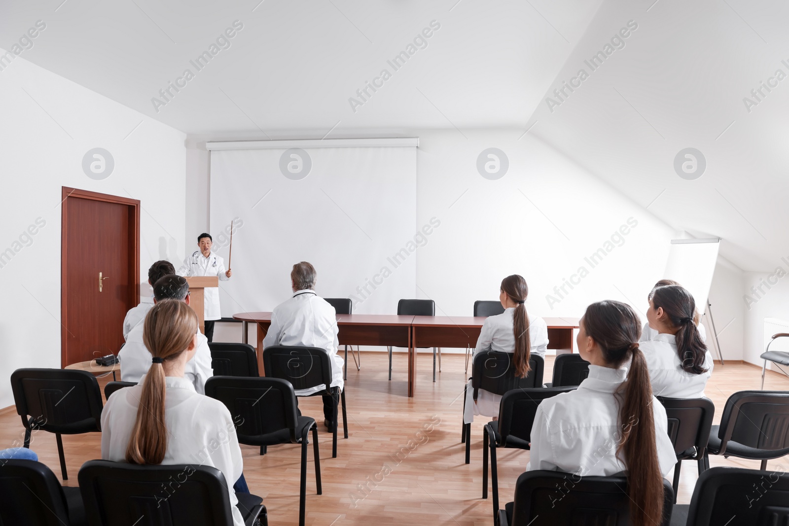 Photo of Doctor giving lecture in conference room with projection screen