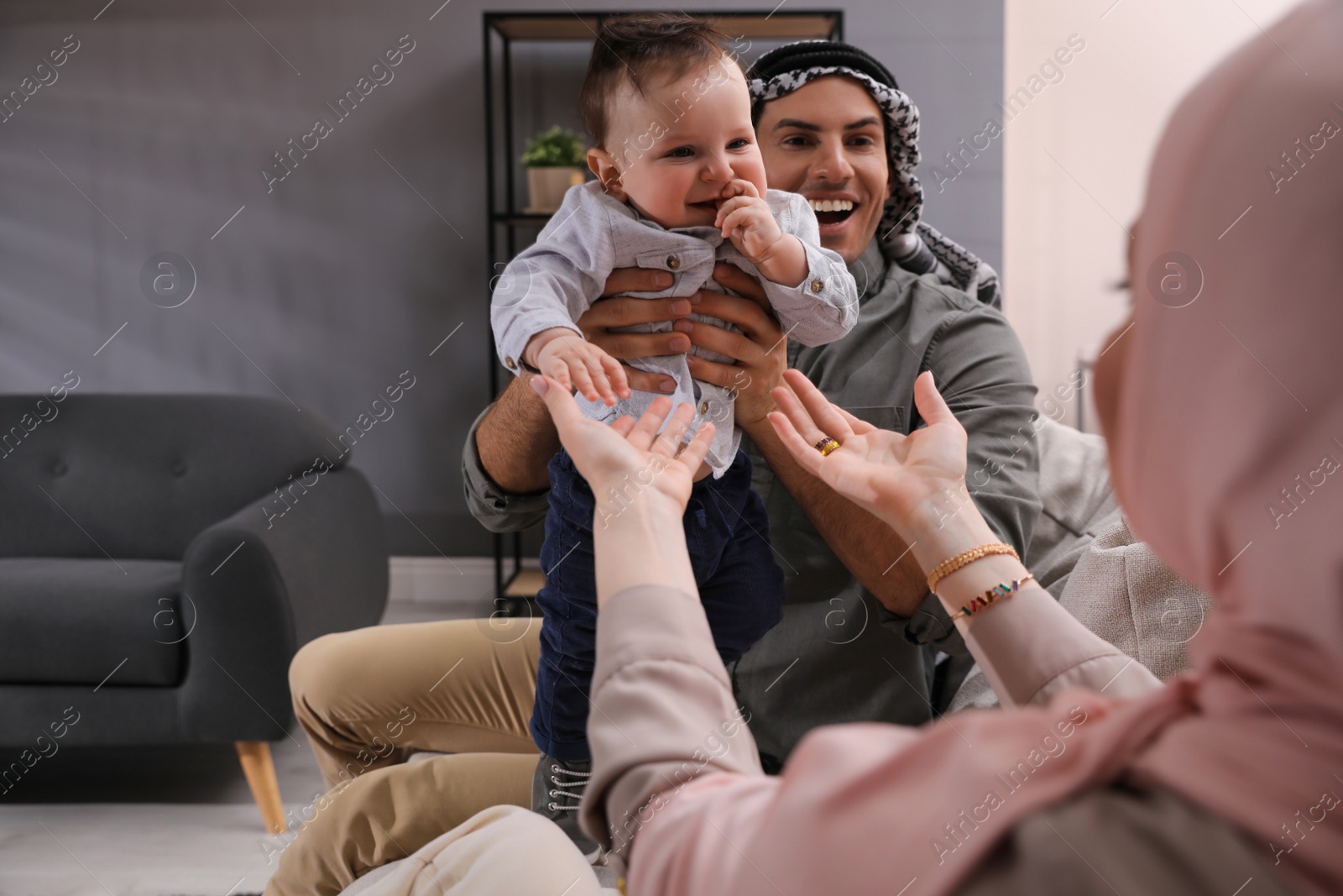 Photo of Happy Muslim family with little son in living room