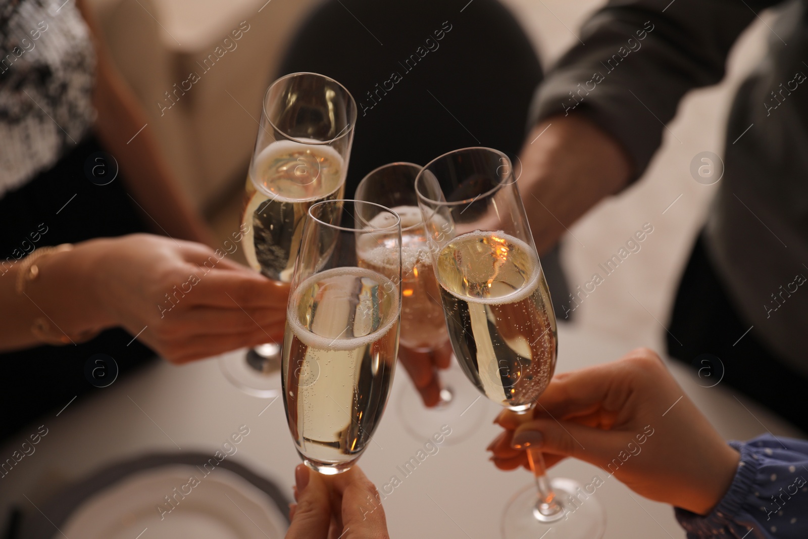 Photo of People clinking glasses with champagne at home, closeup