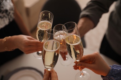 People clinking glasses with champagne at home, closeup