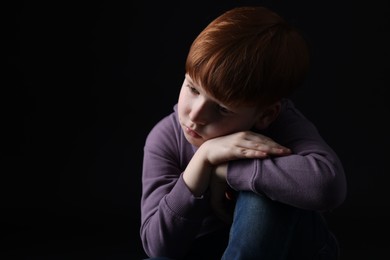 Photo of Portrait of sad little boy on black background, space for text