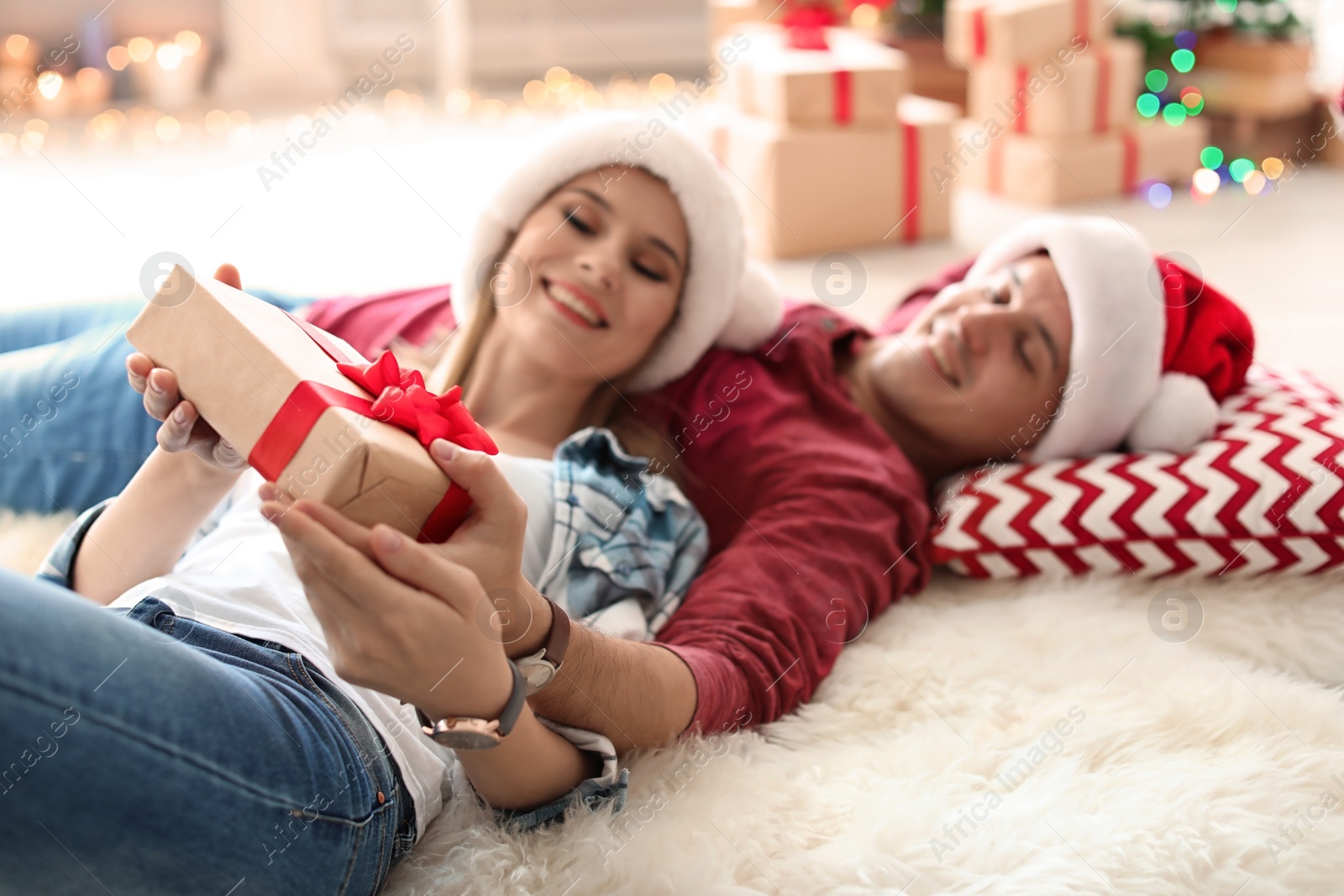 Photo of Young couple with Christmas gift at home