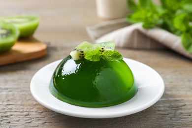 Photo of Delicious fresh green jelly with kiwi slices and mint on wooden table