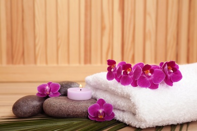 Photo of Spa stones, orchid flowers and towel on wooden table