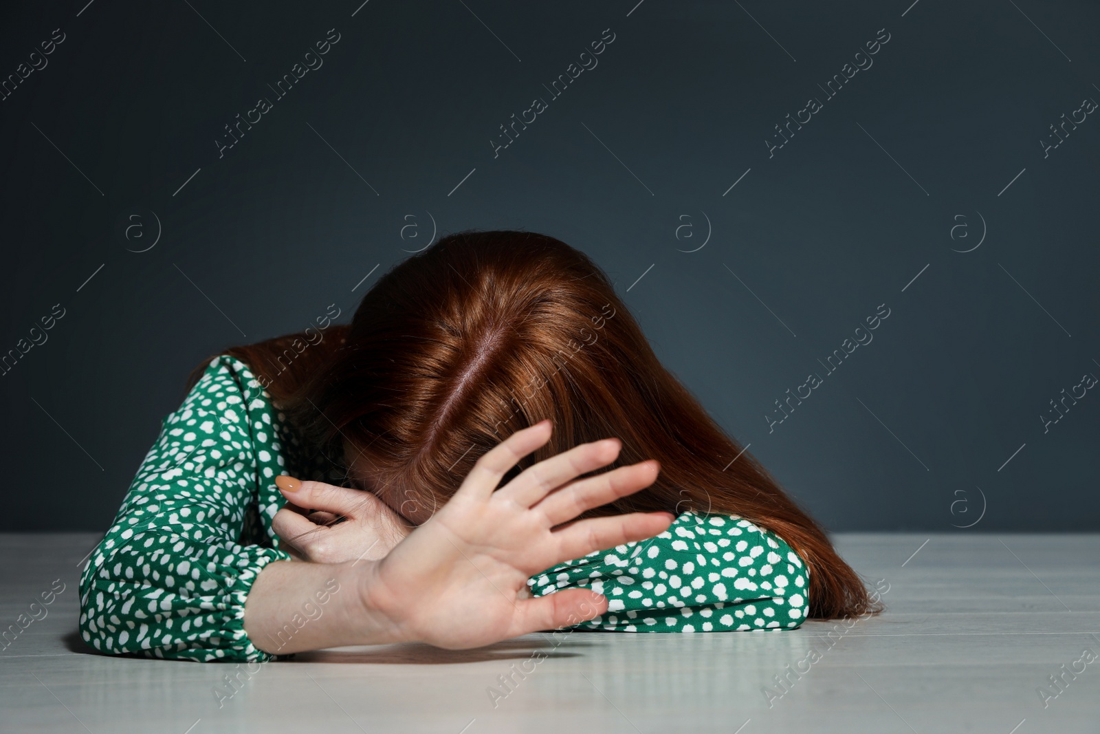 Photo of Young woman making stop gesture while lying on floor indoors