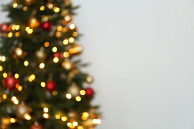 Blurred view of Christmas tree with fairy lights on white background