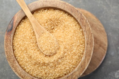 Photo of Brown sugar in bowl and spoon on grey table, top view