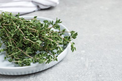 Photo of Bunch of aromatic thyme on light grey table, closeup. Space for text