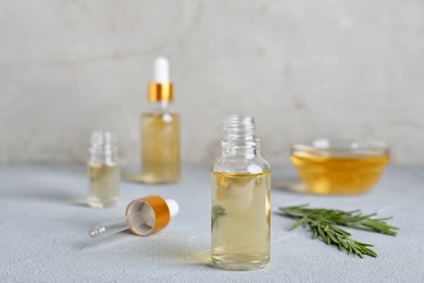 Glass bottle of essential oil, pipette and rosemary on table. Space for text