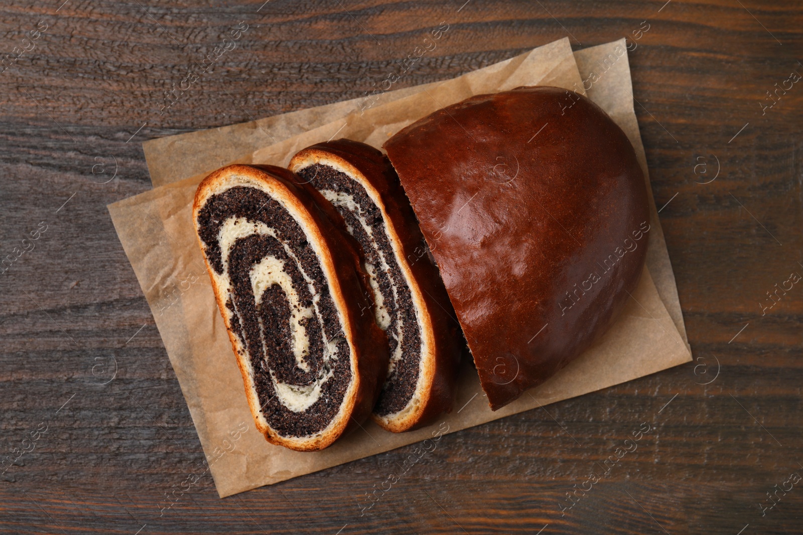 Photo of Cut poppy seed roll on wooden table, top view. Tasty cake