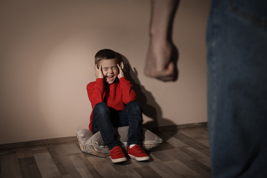 Photo of Man threatening his son indoors. Domestic violence concept