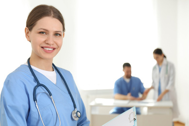 Photo of Portrait of young doctor with clipboard in hospital, space for text. Medical service