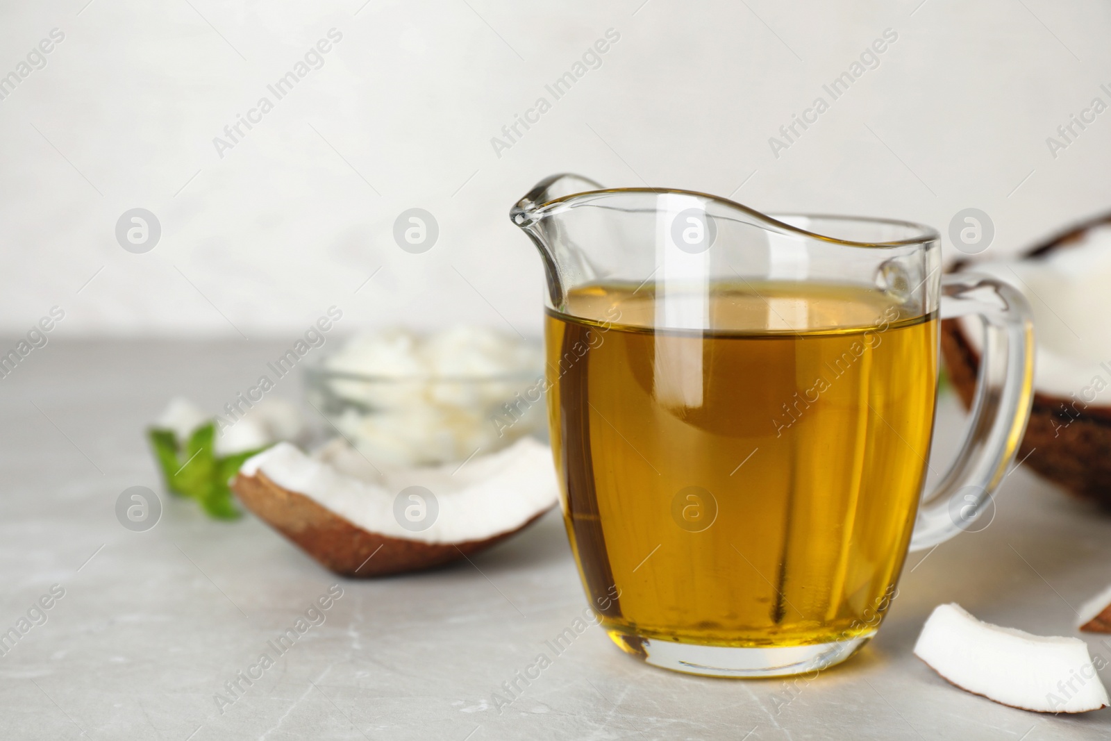 Photo of Pitcher with coconut oil on table. Healthy cooking