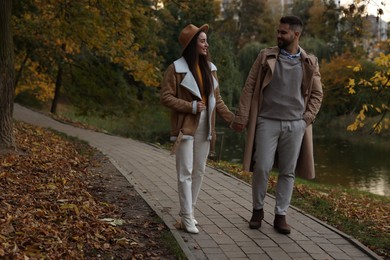 Photo of Happy young couple walking in autumn park, space for text