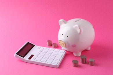Financial savings. Piggy bank, coins and calculator on pink background