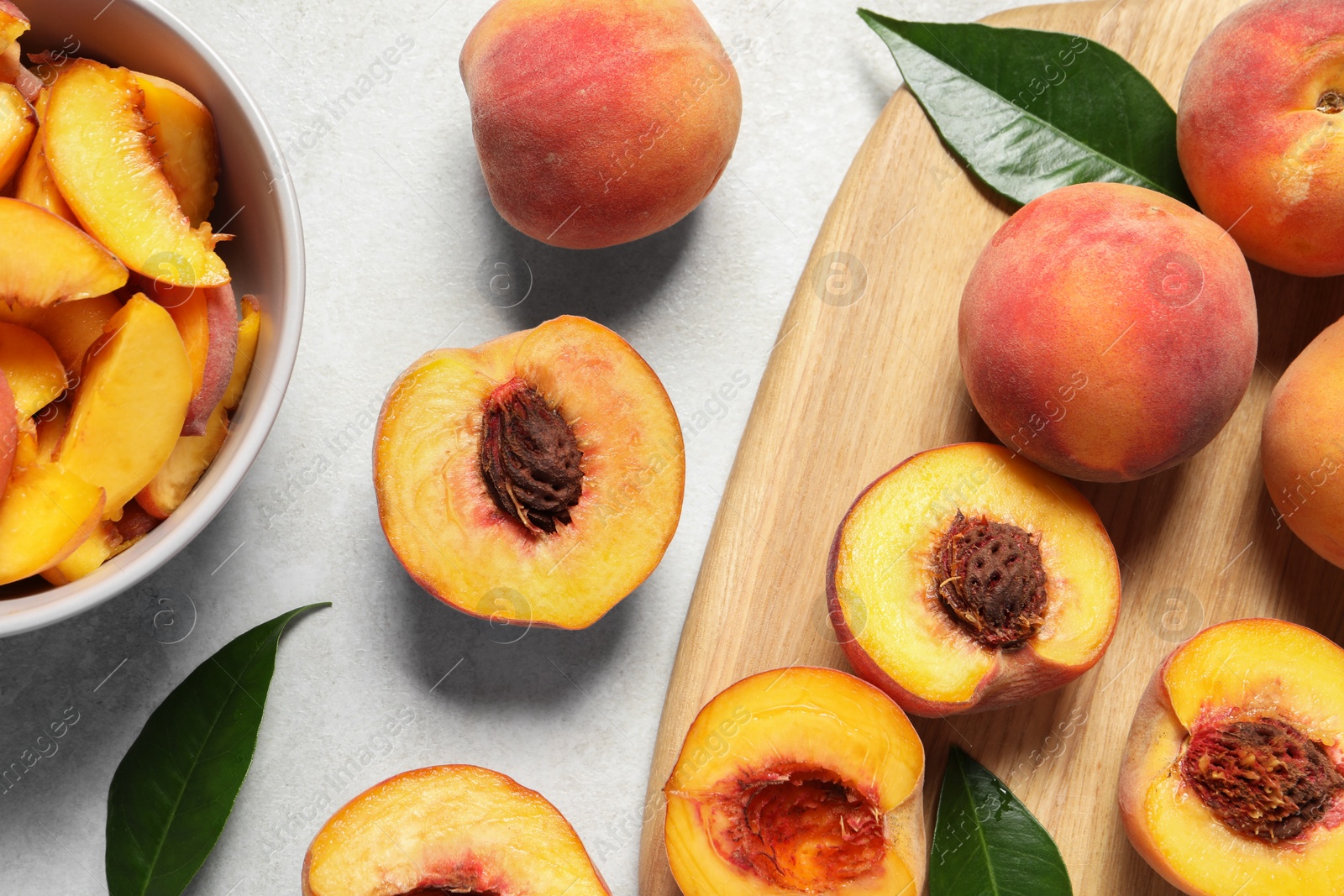 Photo of Delicious juicy peaches and leaves on light grey textured table, flat lay