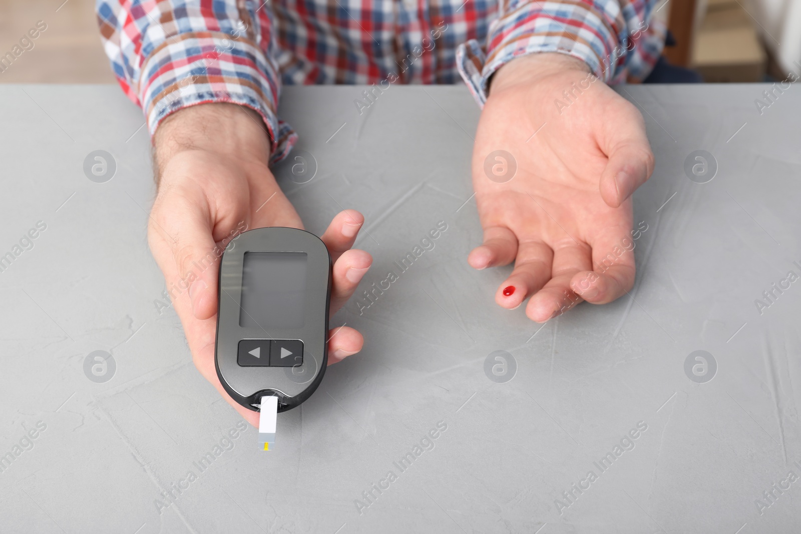 Photo of Man checking blood sugar level with glucometer at table. Diabetes test